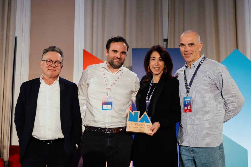 Quatre personnes posant ensemble sur scène, avec un trophée des Prix de l'économie Néo-Aquitains 2024 tenu par une femme au centre.